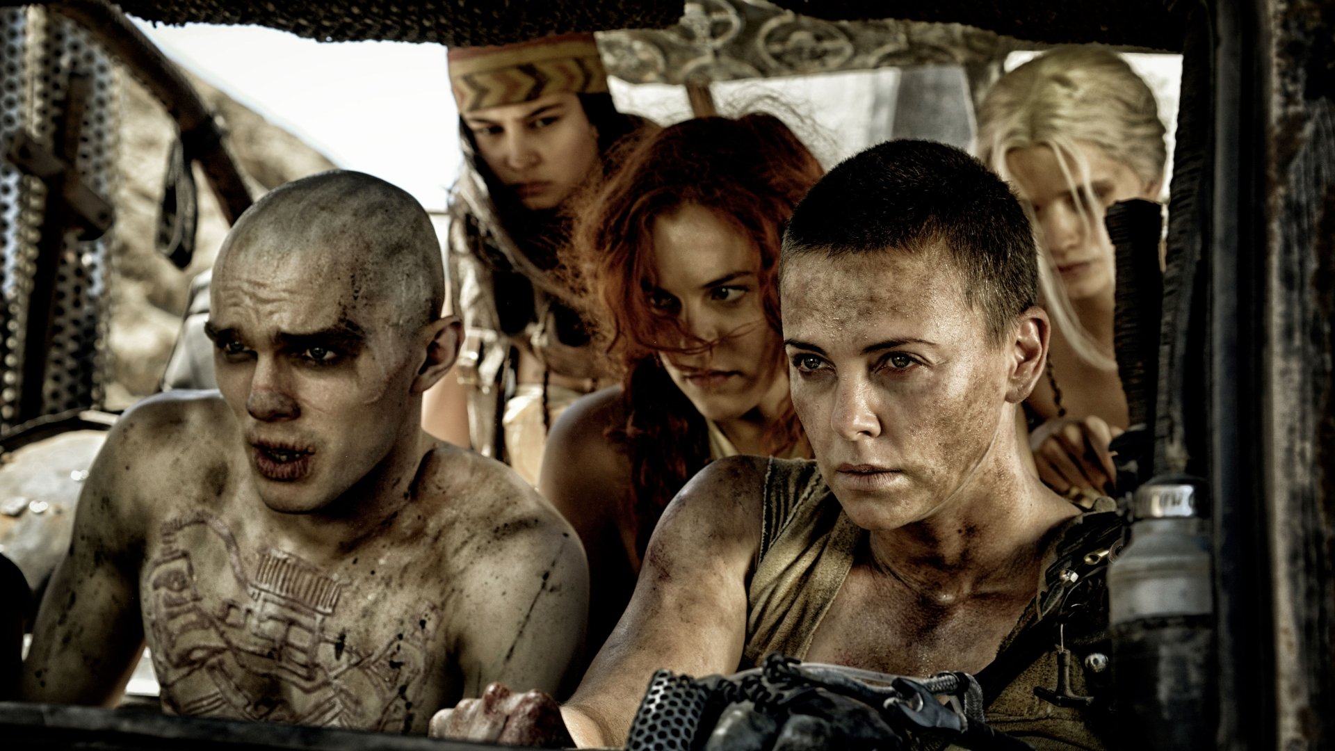 A dynamic scene from *Mad Max: Fury Road*, featuring characters Imperator Furiosa, played by Charlize Theron, and Nux, portrayed by Nicholas Hoult, amidst a tense moment in the post-apocalyptic landscape.