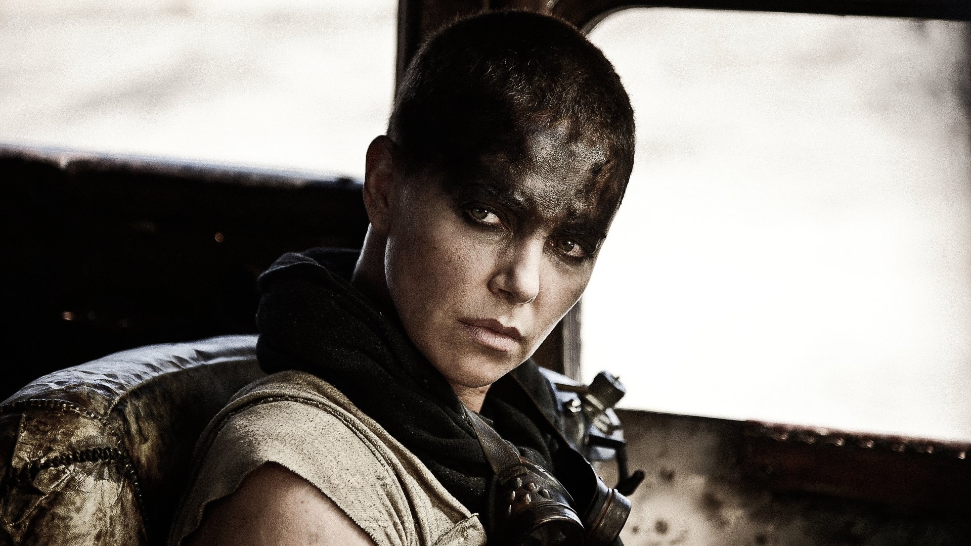 A close-up of Imperator Furiosa, portrayed by Charlize Theron in *Mad Max: Fury Road*, showcasing her fierce expression and dramatic makeup in a gritty, post-apocalyptic setting.
