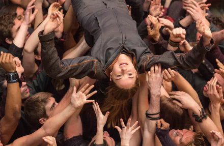A scene from the movie Divergent, featuring a character being lifted by a crowd, showcasing a moment of adrenaline and excitement. This HD image serves as an engaging desktop wallpaper.