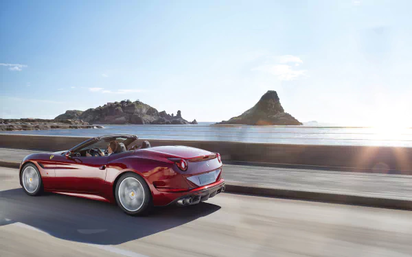 HD desktop wallpaper featuring a sleek red Ferrari California T driving along a coastal road with clear skies and scenic hills in the background.