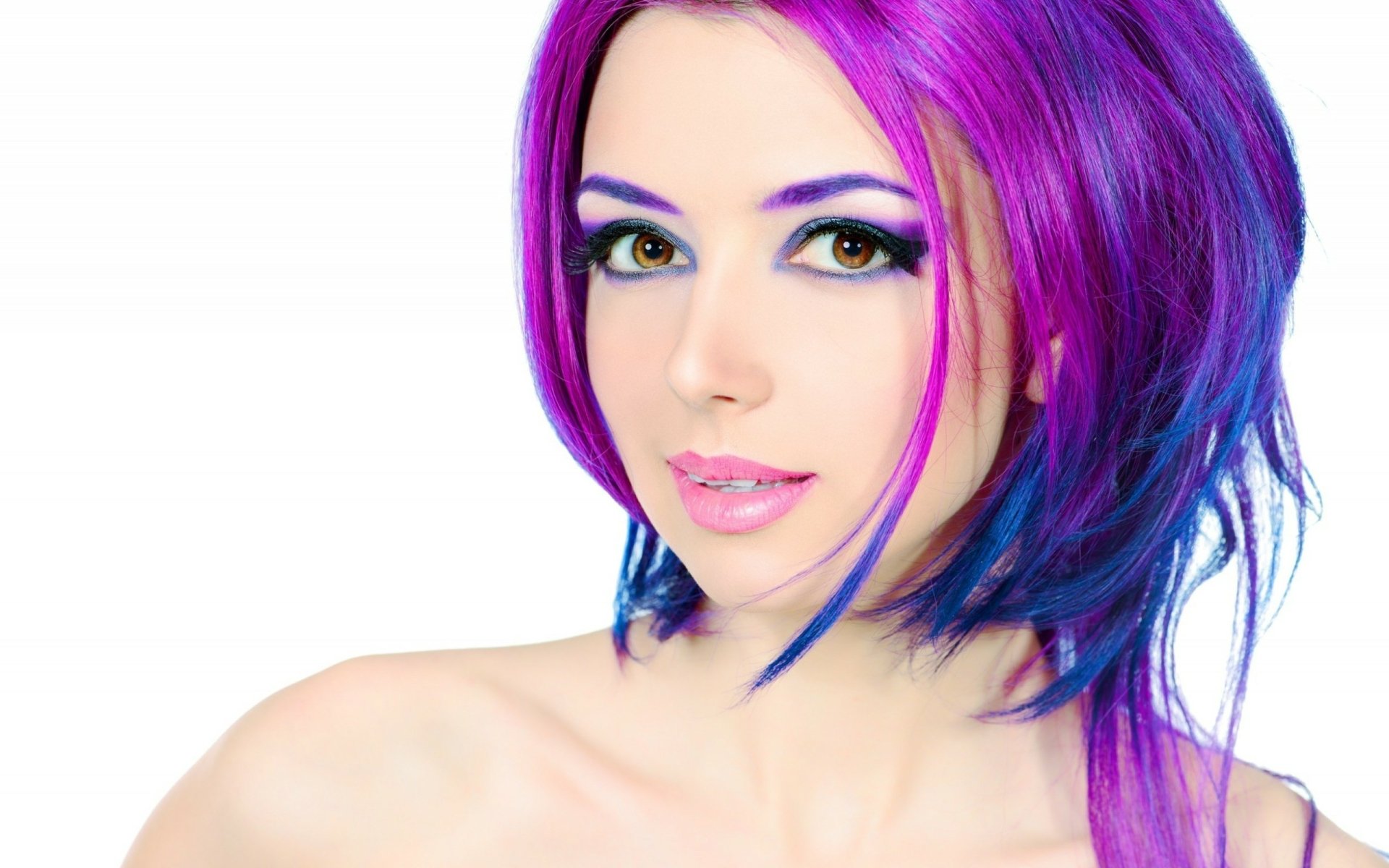 A vibrant model with striking purple and blue hair and bold makeup poses confidently. This HD desktop wallpaper showcases her captivating features.