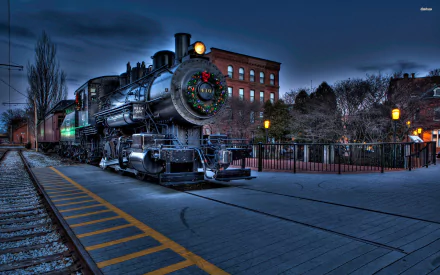 A black steam train at night on tracks near a platform with a brick building and trees in the background, captured in a high-definition PC desktop wallpaper image.