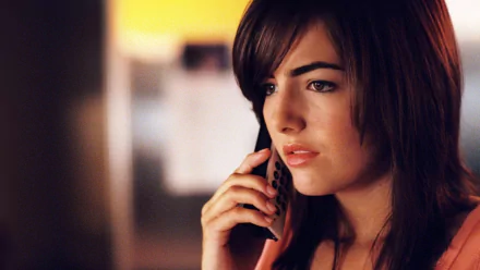 A close-up of Camilla Belle speaking on the phone, featured as a HD desktop wallpaper. The image highlights her expressive features against a softly blurred background.