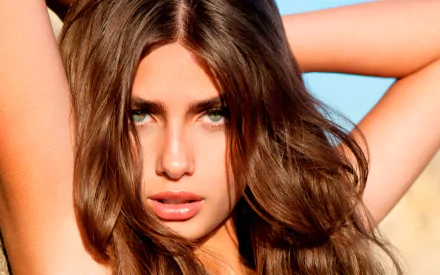 HD PC desktop wallpaper featuring a close-up of American woman Taylor Marie Hill with flowing brown hair and piercing blue eyes against a bright outdoor background.
