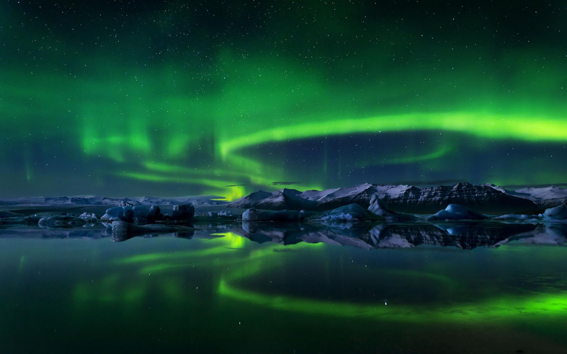 A stunning view of the aurora borealis lighting up the night sky, reflected in a calm body of water, creating a serene and captivating nature scene. HD wallpaper for nature lovers.