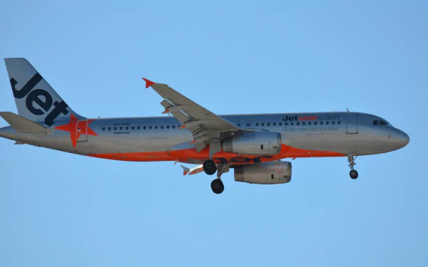 Airbus A320 passenger plane from Jetstar in flight against a clear blue sky, captured in high-definition detail for desktop wallpaper use.