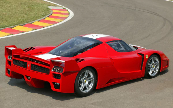 A red Ferrari FXX race car speeds on a curved racetrack, captured in high definition as a dynamic PC desktop wallpaper and background.