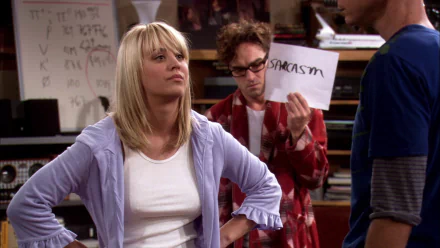 Penny confronts Leonard in a scene from *The Big Bang Theory*, while he holds a sign that reads sarcasm. A humorous moment showcasing the show's witty dynamics.