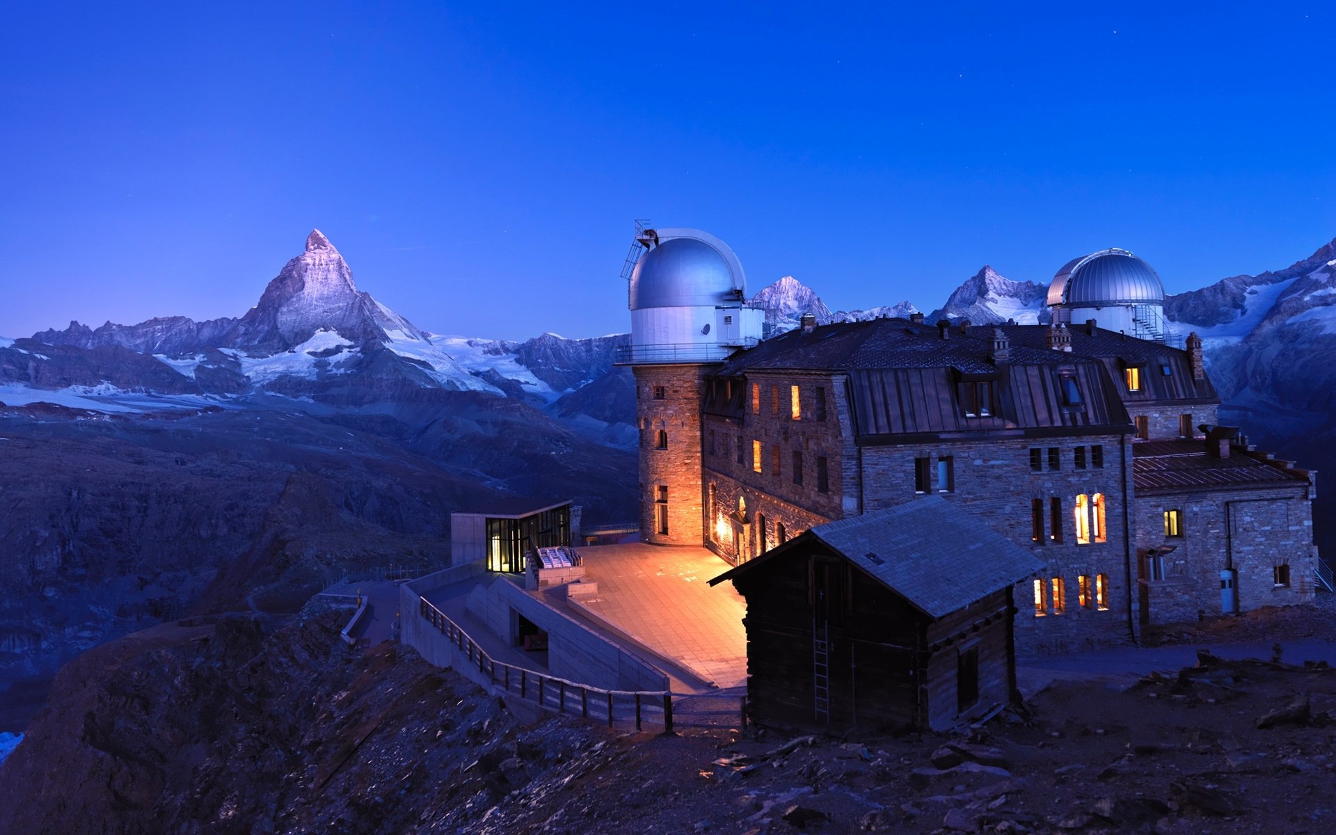 HD PC desktop wallpaper showing Kulmhotel Gornergrat and man-made planetarium domes glowing at dusk on the Alpine ridge with the Matterhorn beyond.