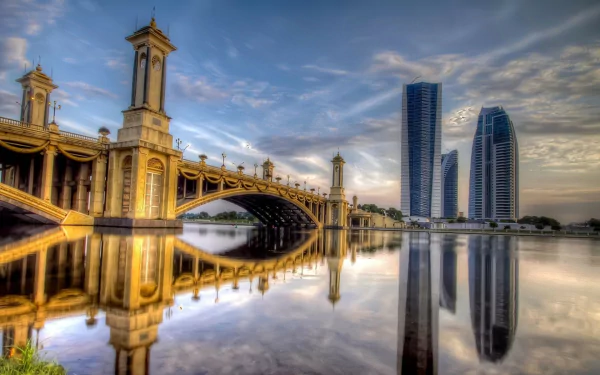 A stunning HD wallpaper of Kuala Lumpur showcasing a majestic bridge reflected in water, surrounded by modern skyscrapers under a vibrant sky. A beautiful man-made landscape in Malaysia.