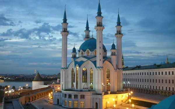 Night view of Qolşärif Mosque with illuminated minarets in Kazan, Russia, set against a cloudy sky and cityscape, captured in high-definition.