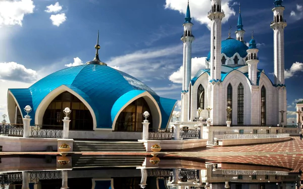 HD desktop wallpaper of the Qolşärif Mosque, a prominent religious landmark in Kazan, Russia, with blue domes and slender minarets reflected on the polished plaza under a dramatic sky.