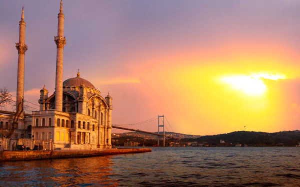 A stunning HD wallpaper featuring the Ortaköy Mosque in Istanbul at sunset, with the Bosphorus Bridge in the background, capturing the beauty of the city's skyline.