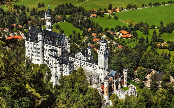Aerial view of Germany’s Neuschwanstein Castle surrounded by lush greenery, captured in HD as a detailed and vibrant man-made architectural marvel.