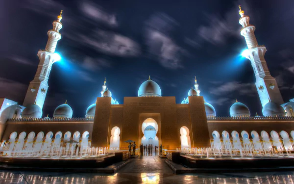 Night view of the illuminated Sheikh Zayed Grand Mosque in Abu Dhabi, showcasing its grand architecture and serene reflection, captured in HD for a desktop wallpaper.