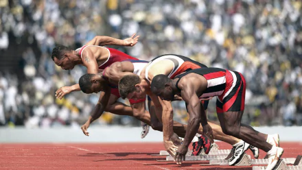 Track & Field sprinters launching from starting blocks in an intense sports running action shot — HD PC desktop wallpaper/background.
