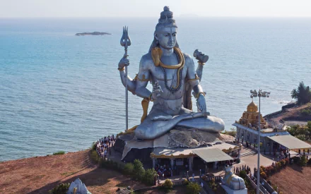 A stunning HD wallpaper showcasing the colossal statue of Lord Shiva at Murudeshwara, India, set against the backdrop of the tranquil sea, epitomizing Hinduism and religious magnificence.