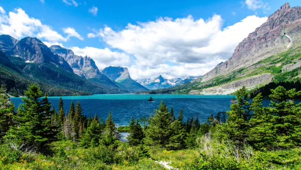 Saint Mary Lake panorama: turquoise water, pine-forested shore and jagged mountain peaks beneath a bright sky — 2K Quad HD PC desktop wallpaper and background.
