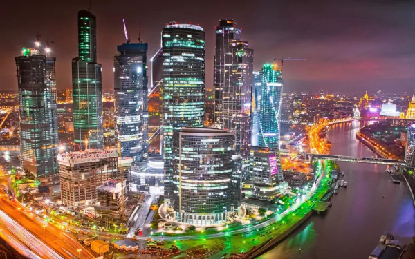 Nighttime view of Moscow's illuminated skyscrapers and the river, showcasing the modern man-made skyline of Russia in HD quality.