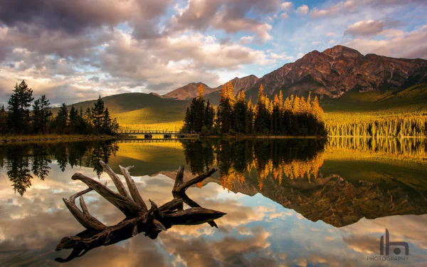 Sunlit mountains and clouds reflect on the calm lake in Jasper National Park, Alberta, Canada, showcasing pristine nature in this HD desktop wallpaper.