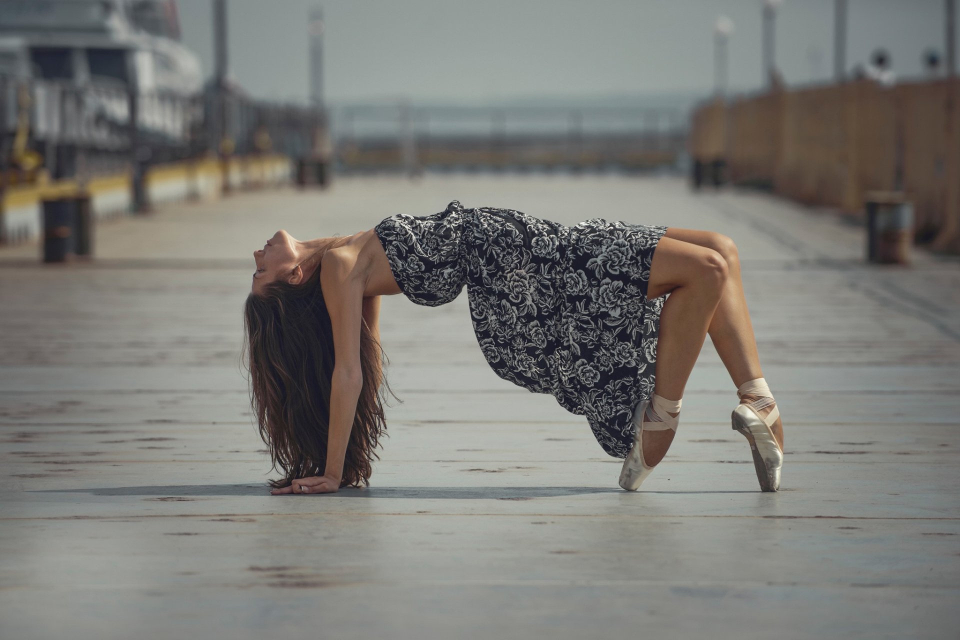 HD desktop wallpaper featuring a woman in a graceful arching pose on an empty pier, conveying a serene mood.