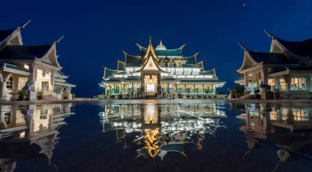 HD desktop wallpaper featuring the illuminated Wat Pa Phu Kon temple in Udon Thani, Thailand, reflecting beautifully on a calm surface at night.