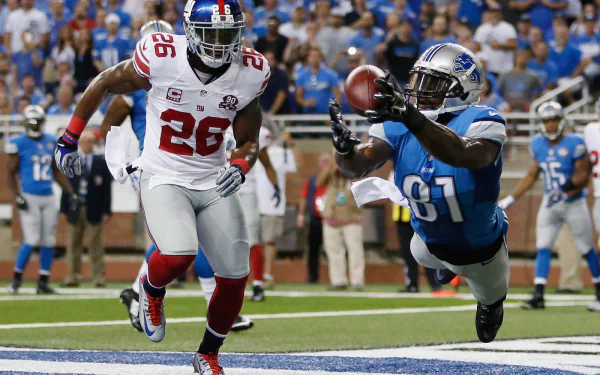 HD PC desktop wallpaper featuring a Detroit Lions player making a diving catch during a football game, with opposing team defenders in the background.