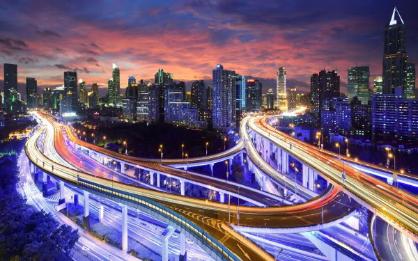 A vibrant sunset over Shanghai illuminates the city's skyline, showcasing a dynamic road network intertwined with glowing traffic, creating an enchanting night scene.