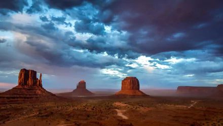 HD PC desktop wallpaper featuring dramatic clouds over the desert landscape of Monument Valley, showcasing iconic rock formations and vibrant natural scenery.