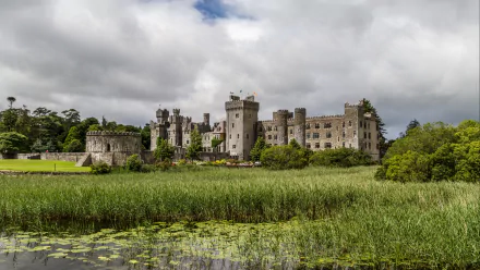 HD desktop wallpaper showcasing the man-made Ashford Castle surrounded by lush greenery under a cloudy sky.