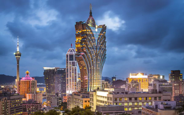 Nighttime cityscape of Macau, China, featuring illuminated man-made skyscrapers under a cloudy sky, captured in high definition.