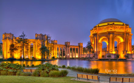 The illuminated Palace of Fine Arts in San Francisco stands majestically by the water at twilight, showcasing intricate architecture against a deep blue sky.