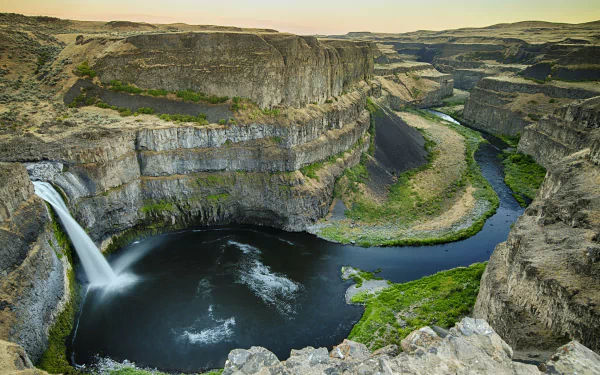A stunning view of Palouse Falls cascading into a deep canyon, surrounded by lush greenery and rugged rock formations in Palouse Canyon, Washington. A captivating nature scene.