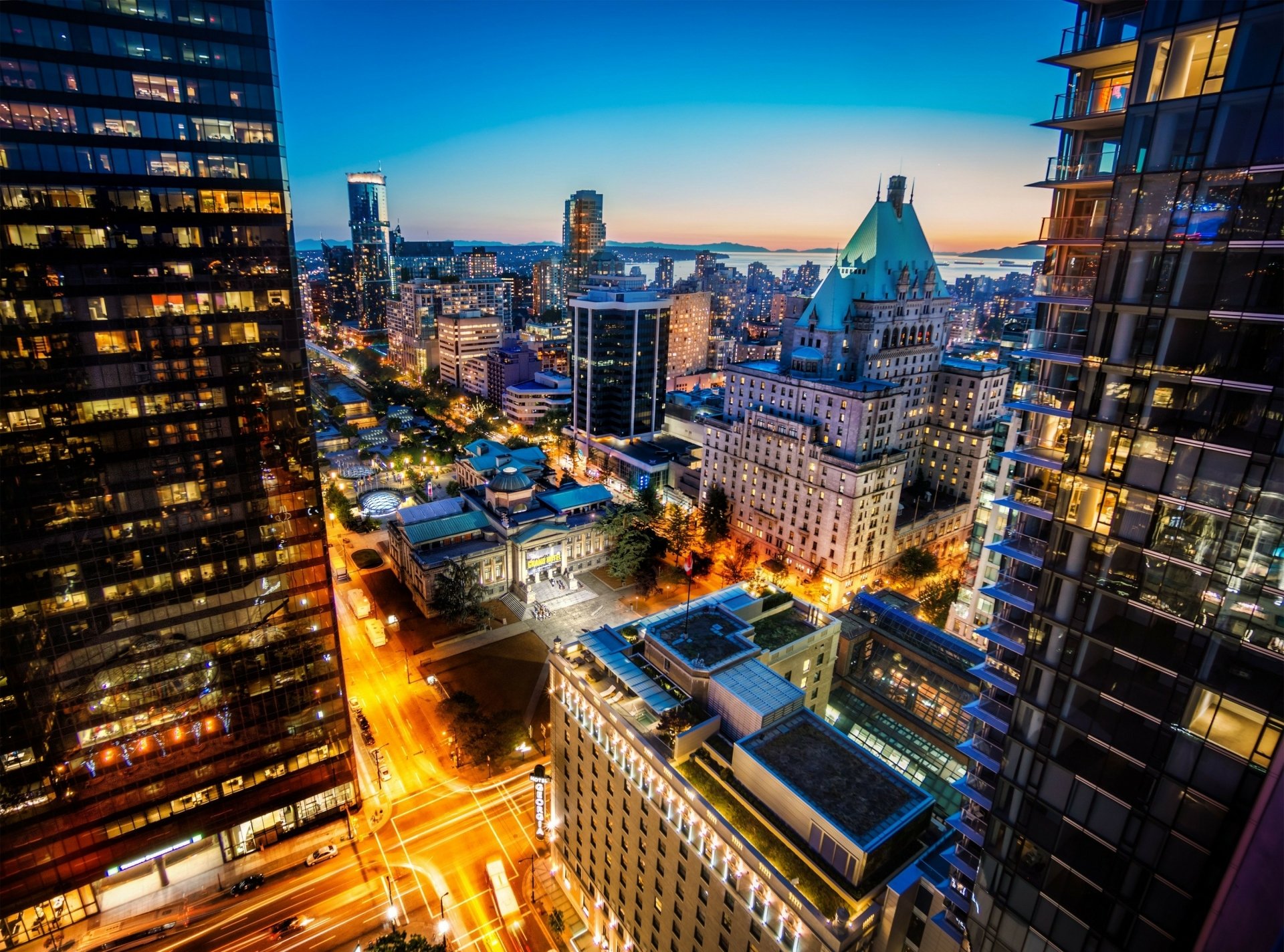 Vibrant nighttime cityscape of downtown Vancouver, British Columbia, Canada, showcasing illuminated skyscrapers and urban architecture in this HD desktop wallpaper.