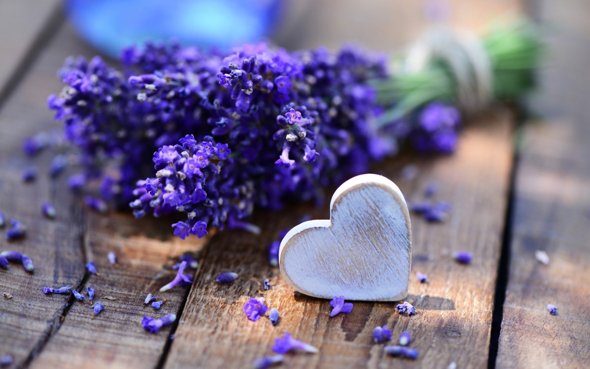 A close-up of a lavender bouquet with a silver heart placed beside it, set on a rustic wooden surface, creating an artistic representation of love. HD wallpaper and background.