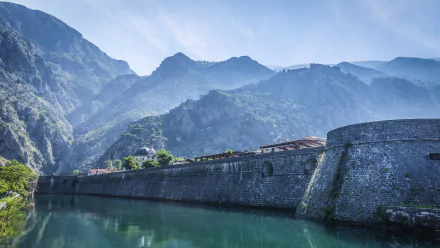 A stunning 4K Ultra HD wallpaper featuring the imposing man-made walls of Kotor set against a backdrop of majestic mountains and tranquil waters.