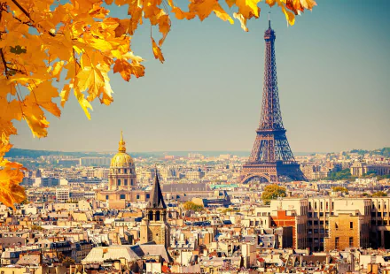 A high-definition desktop wallpaper featuring the Eiffel Tower in Paris, France, with golden autumn leaves in the foreground and the city's scenic skyline in the background.