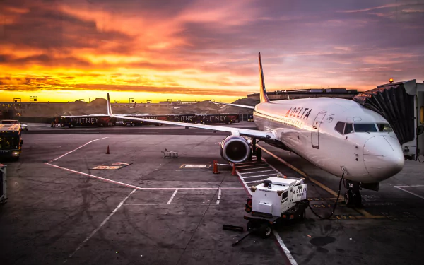 A Boeing 737 parked at an airport gate, bathed in the warm hues of a sunset, creating a stunning HD desktop wallpaper and background.