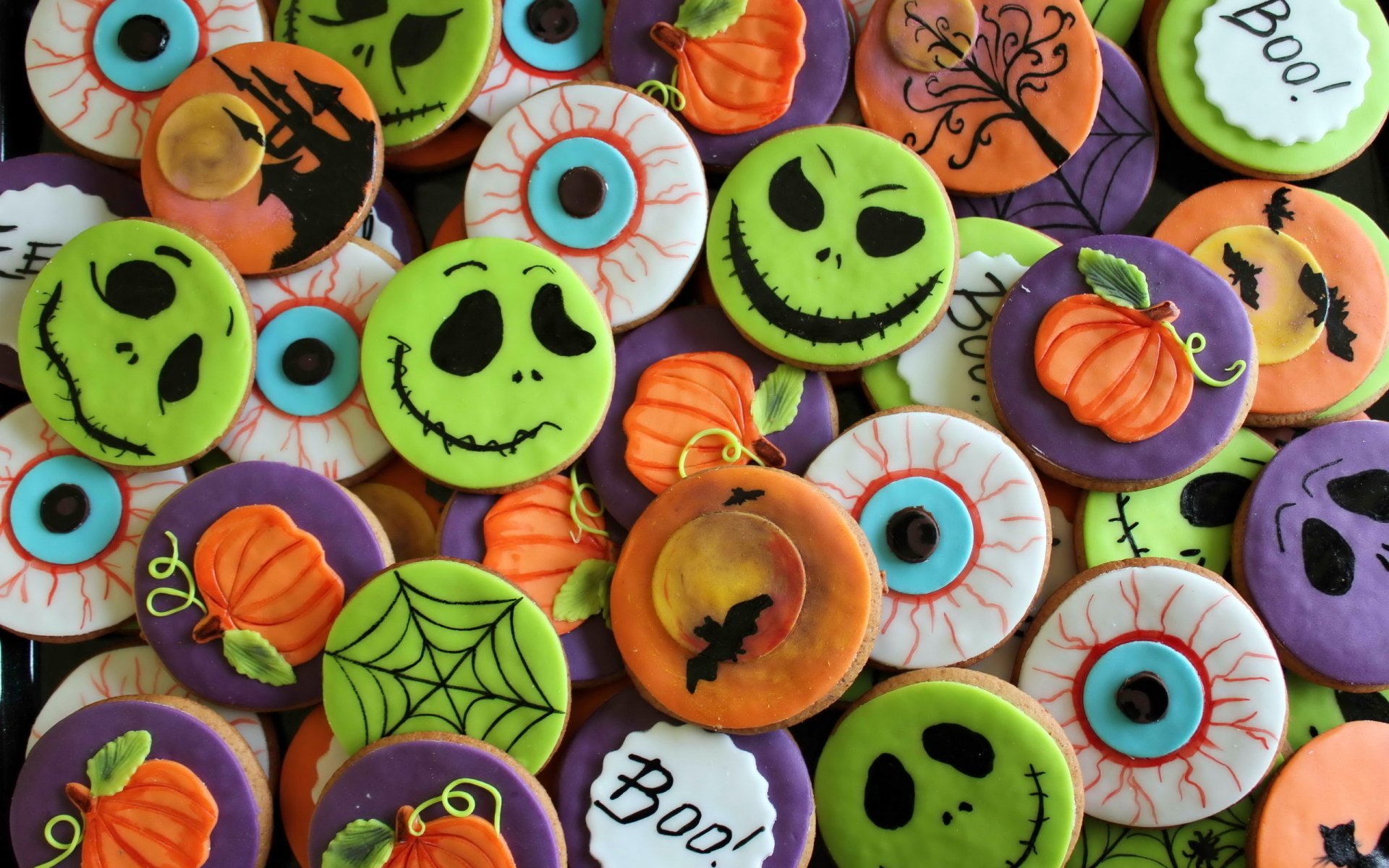 Colorful Halloween-themed biscuits and cookies decorated with pumpkins, spooky faces, spider webs, and eyeballs, arranged as a vibrant HD desktop wallpaper background.