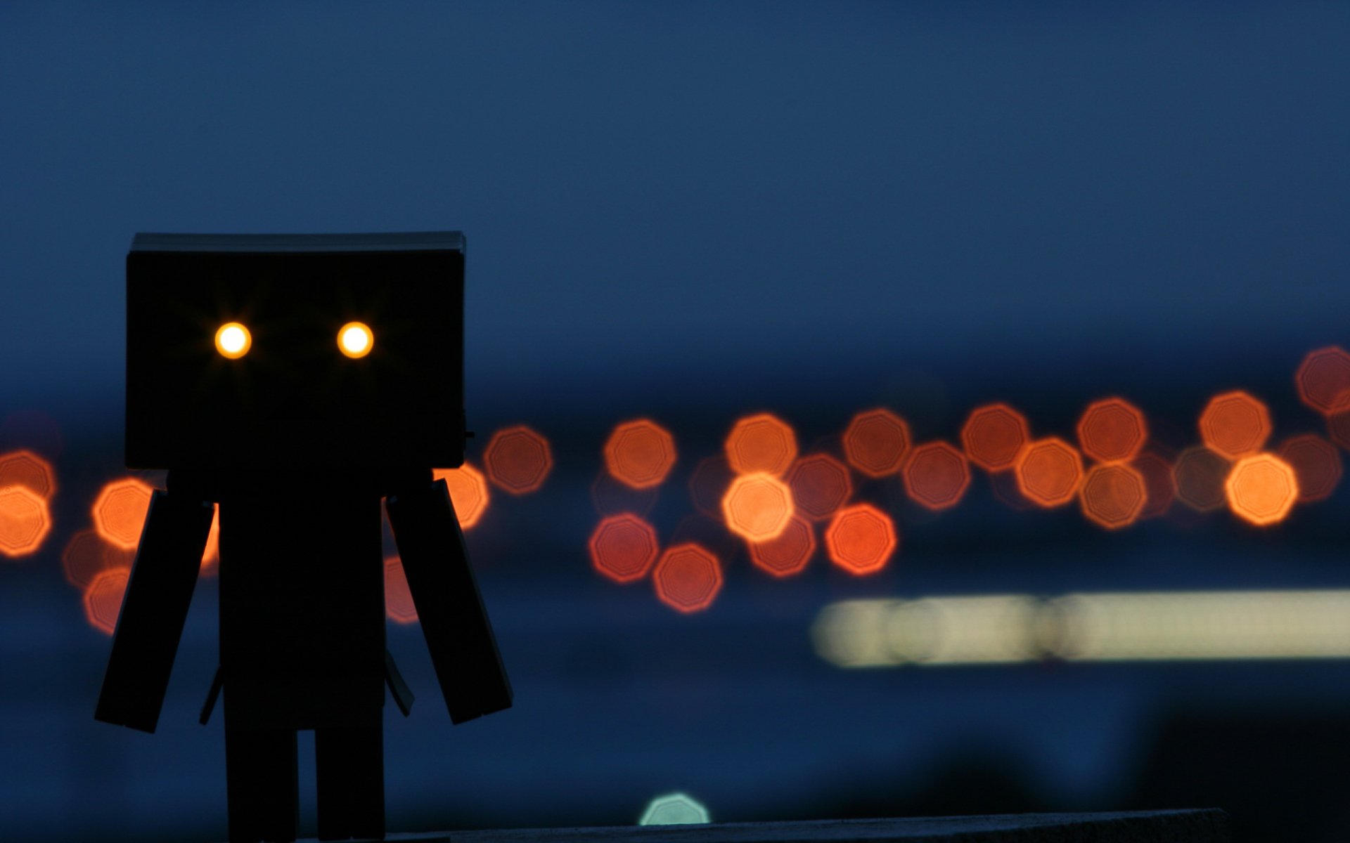 HD PC desktop wallpaper featuring a silhouetted Danbo figure against a blurred cityscape with warm bokeh lights in the background.