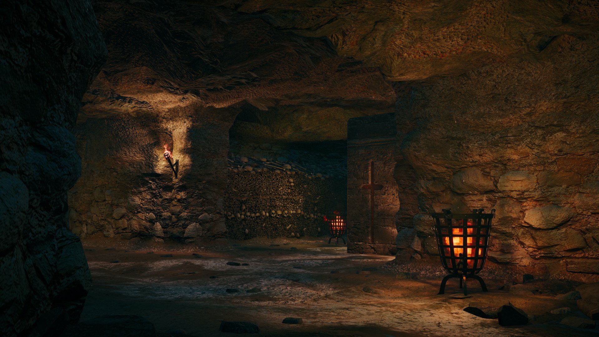 HD wallpaper from Assassin's Creed: Unity, showcasing a dimly lit underground cave with stone walls and illuminated torches, creating an immersive atmosphere.