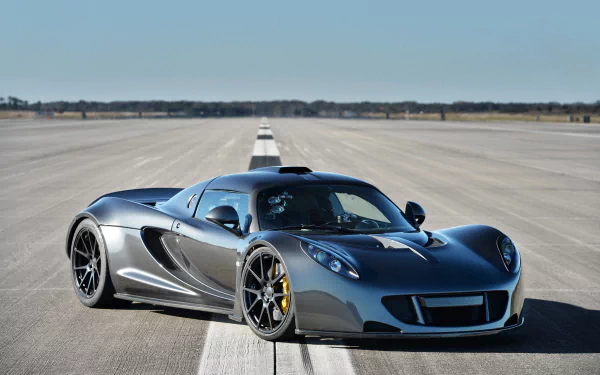 Silver Hennessey Venom GT supercar parked on an open runway, featured as an HD PC desktop wallpaper and background showcasing its sleek design and performance.