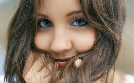 HD desktop wallpaper featuring a close-up of a woman with captivating blue eyes and a playful expression.