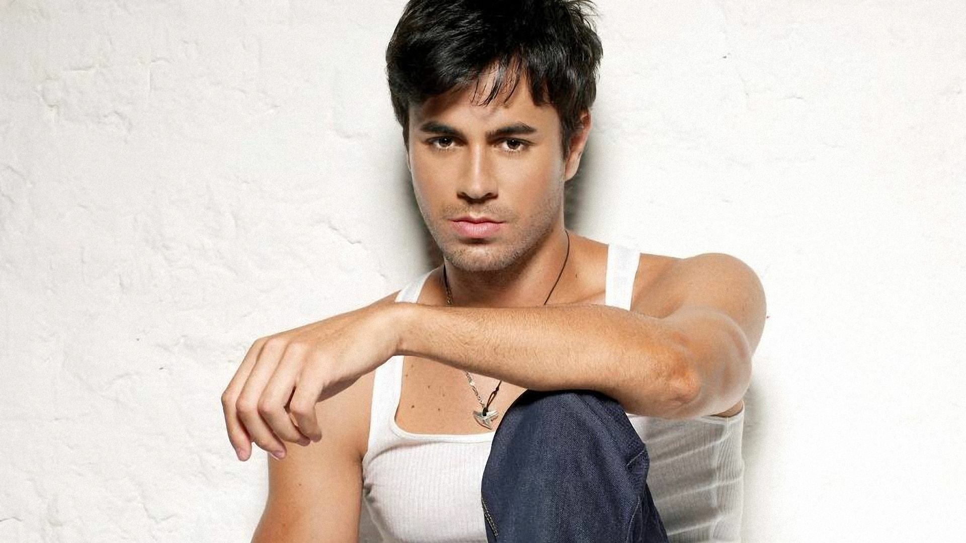 Enrique Iglesias poses confidently in a casual outfit against a textured background. This HD wallpaper captures the essence of his music and charisma.