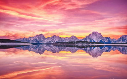 HD PC desktop wallpaper and background: vivid pink-orange sunset over jagged mountains mirrored in a glassy lake, serene nature reflection.