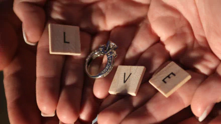 HD desktop wallpaper of hands holding wooden letter tiles forming the word LOVE with an engagement ring, conveying an artistic expression of love.