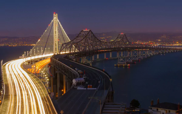Nighttime view of the Bay Bridge connecting Oakland and San Francisco, captured in stunning 4K Ultra HD with city lights glowing in the background.