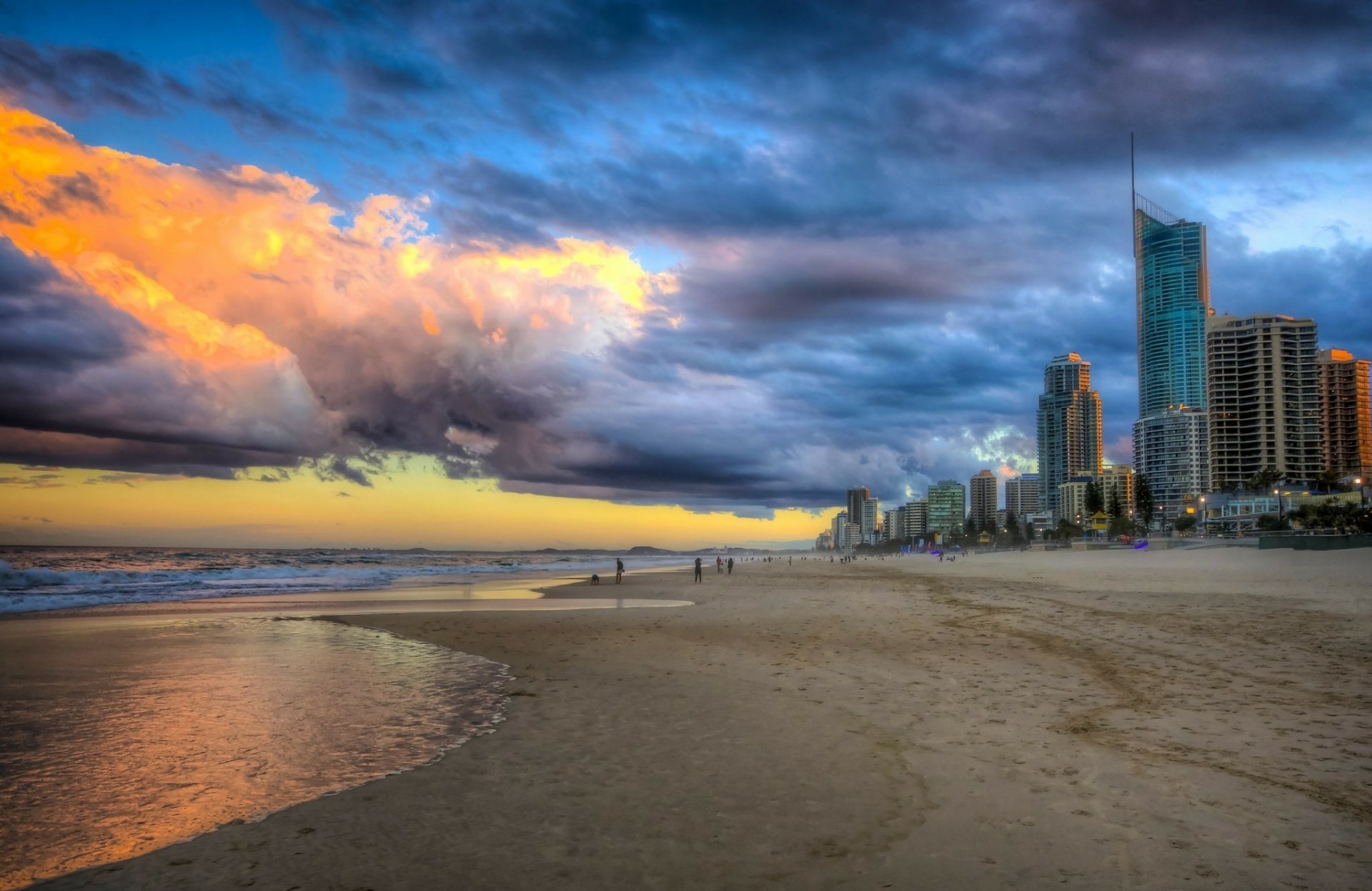 Sunset over the Gold Coast skyline and beach in Australia, with dramatic clouds and calm waters along the coastline in this HD desktop wallpaper.