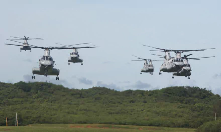 A formation of Boeing Vertol CH-46 Sea Knight helicopters flying over green terrain, showcasing military aircraft used by the Marines in an HD desktop wallpaper background.