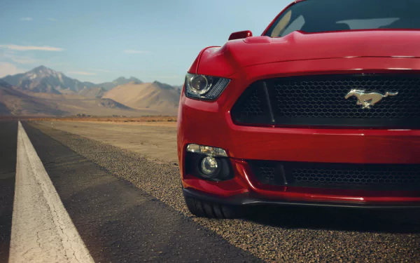 Close-up of a red Ford Mustang parked on a desert road with mountains in the background, captured in 4K Ultra HD for PC desktop wallpaper and background.